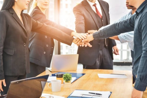 group of people joining hand over a table for business